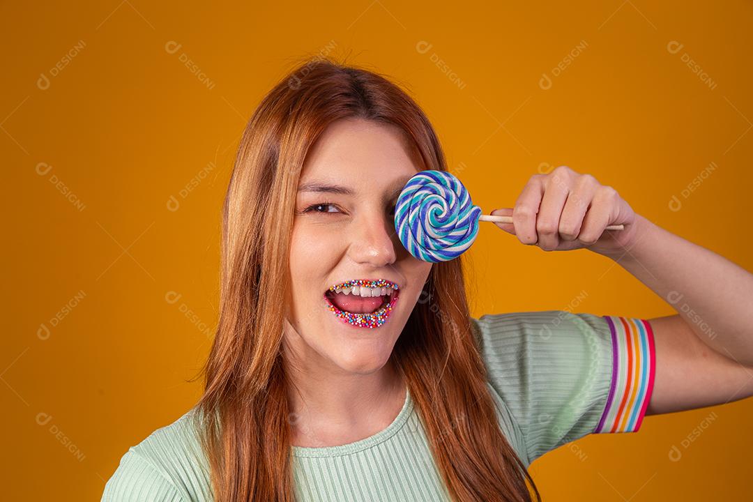 Linda Jovem Ruiva cobrindo um olho com um pirulito azul