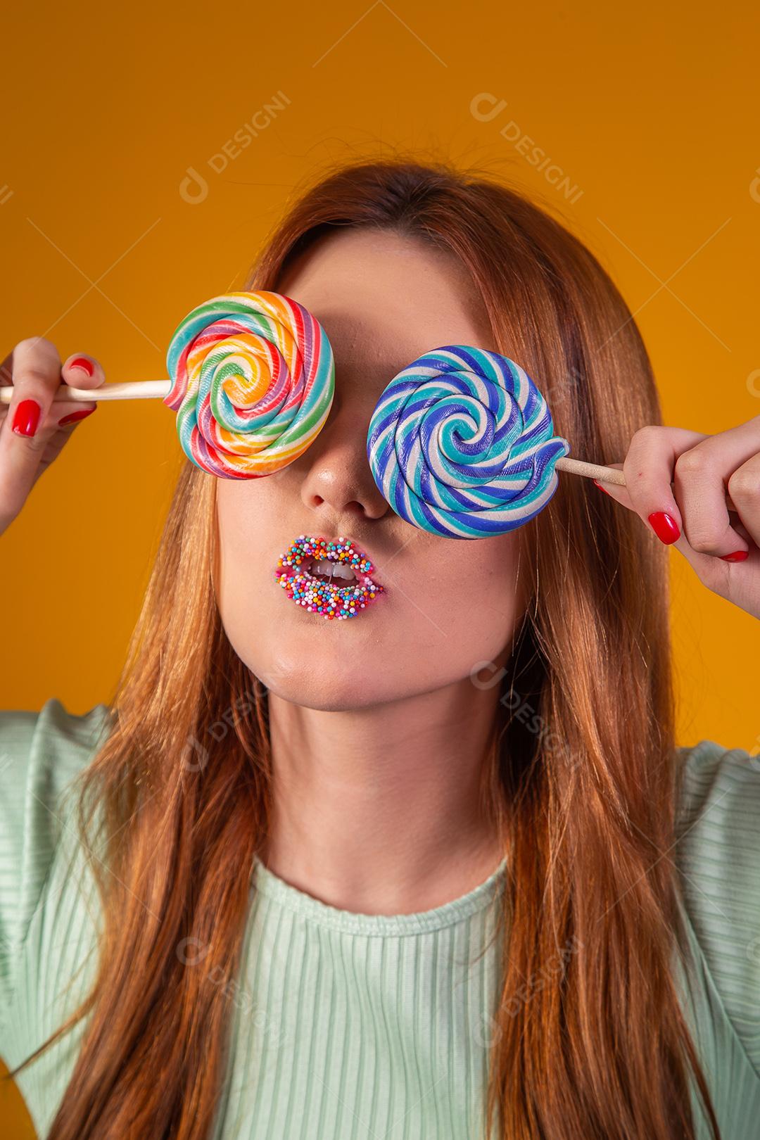 Linda Jovem Ruiva cobrindo os olhos com um pirulitos