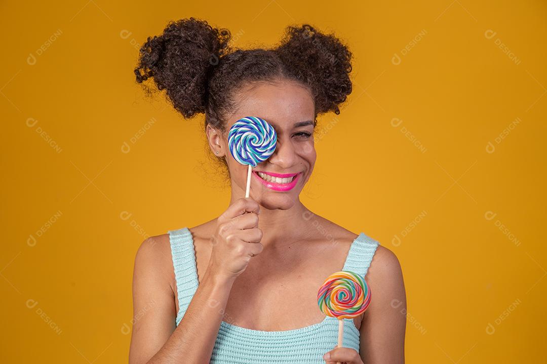 Linda Jovem Afro cobrindo um olho com um pirulito azul