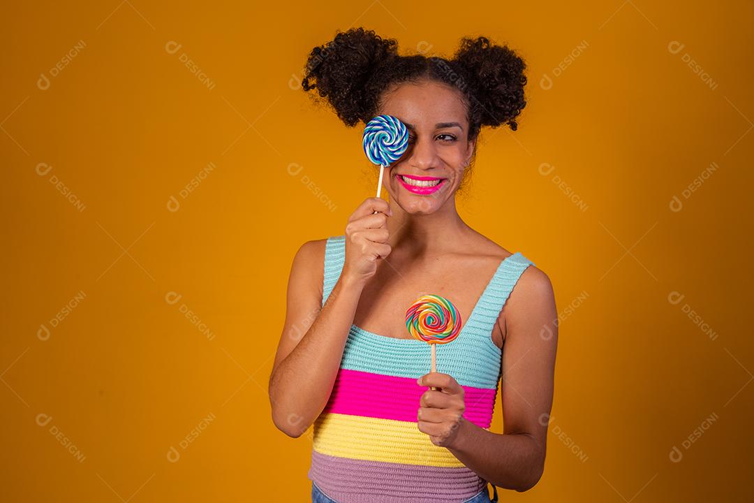 Linda Jovem Afro cobrindo um olho com um pirulito azul