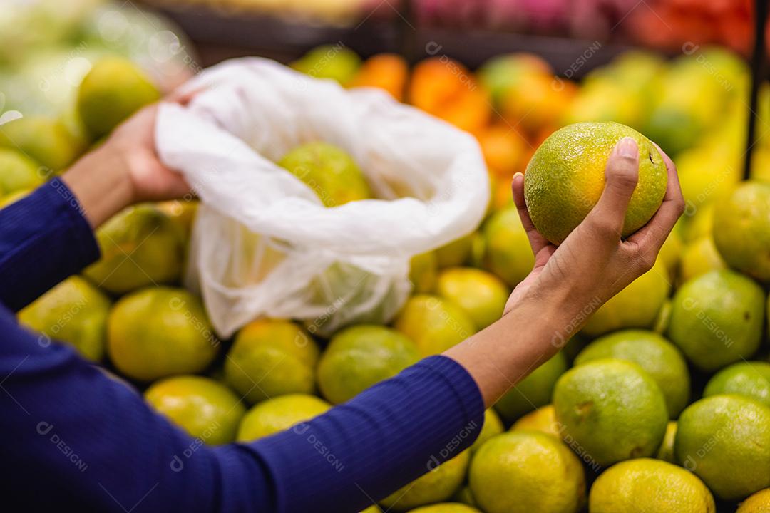 jovem no supermercado comprando laranja