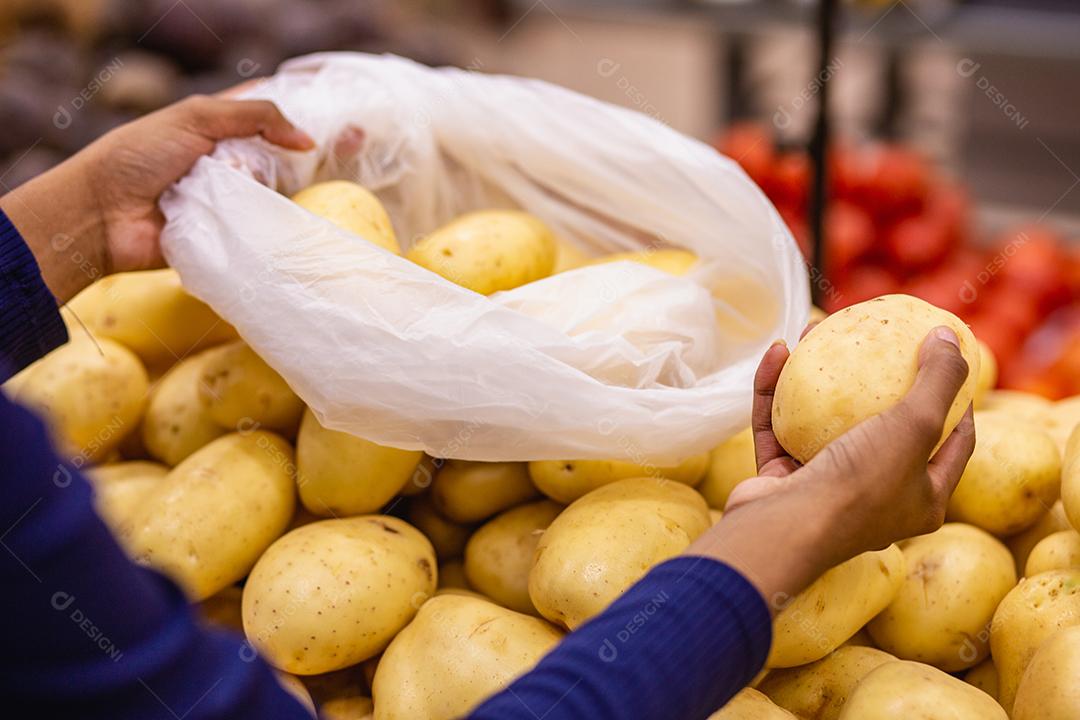 mão de mulher selecionando batatas no mercado