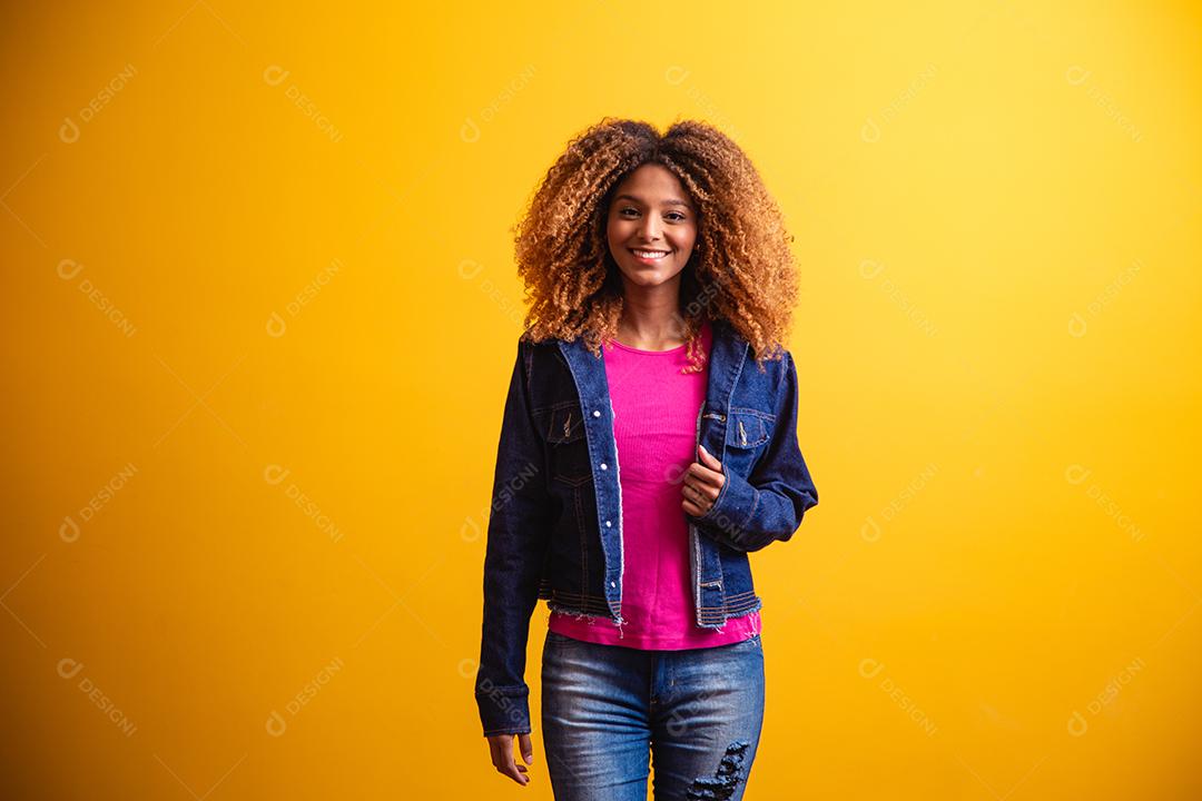 mulher estudante africana sorrindo sobre fundo amarelo.