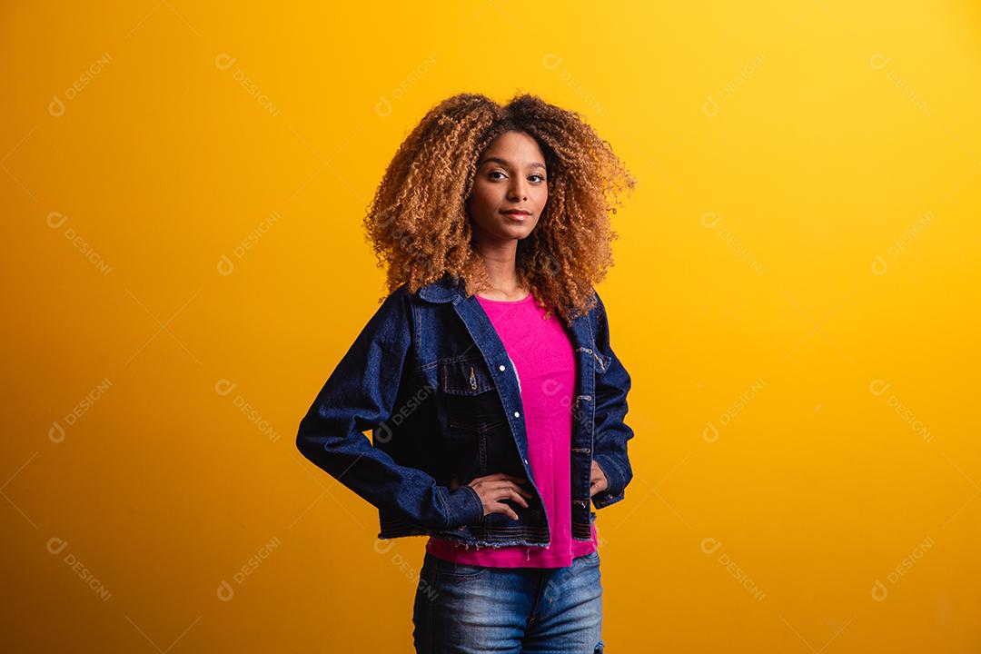 mulher estudante africana sorrindo sobre fundo amarelo.