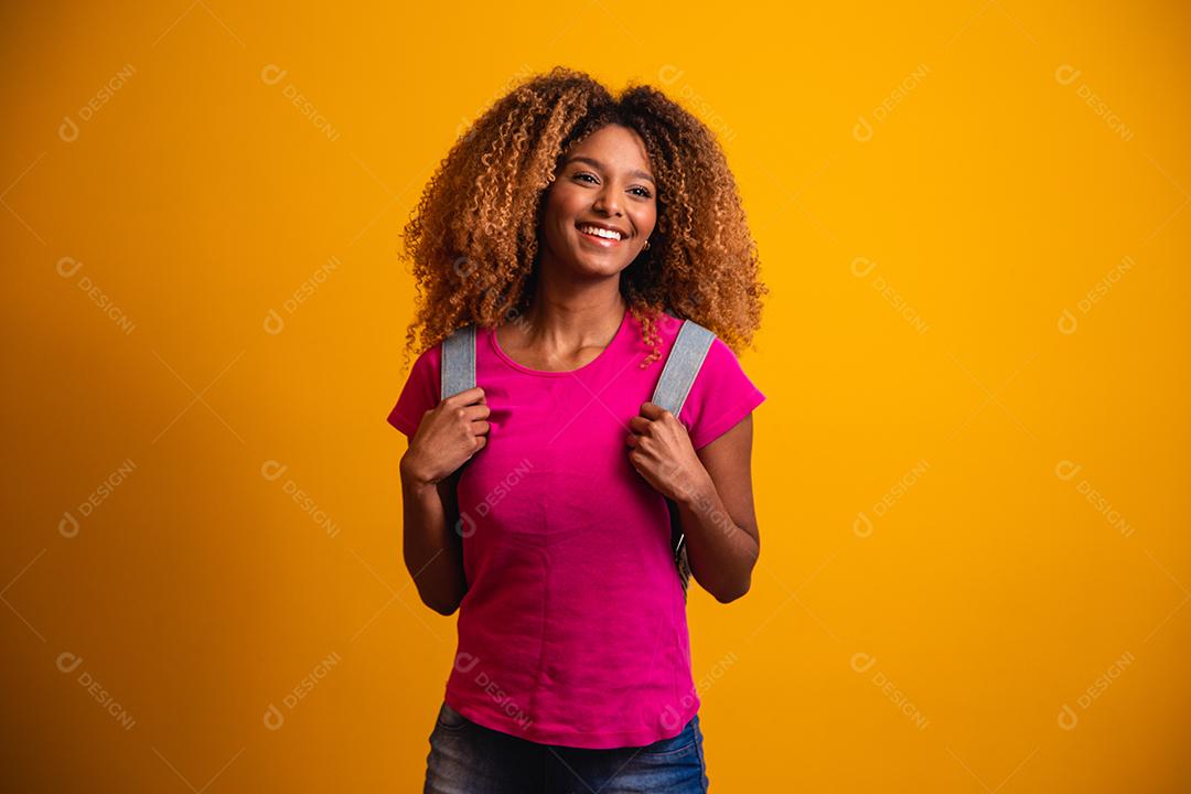 jovem afro com mochila nas costas em fundo amarelo. jovem estudante sorrindo