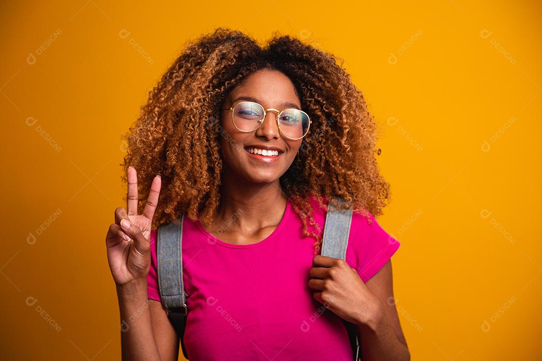 jovem afro com mochila nas costas em fundo amarelo. jovem estudante sorrindo