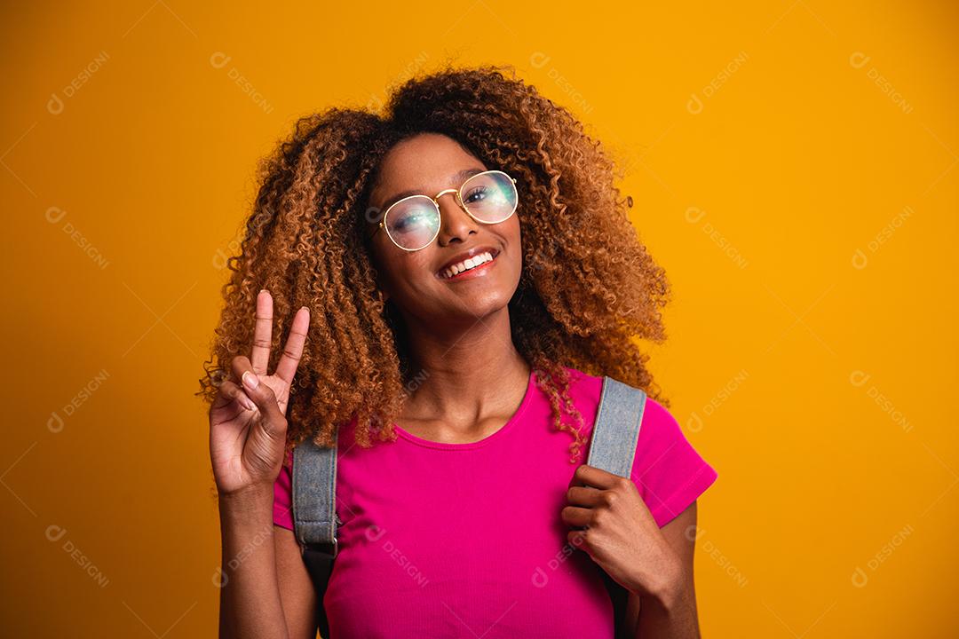 jovem afro com mochila nas costas em fundo amarelo. jovem estudante sorrindo