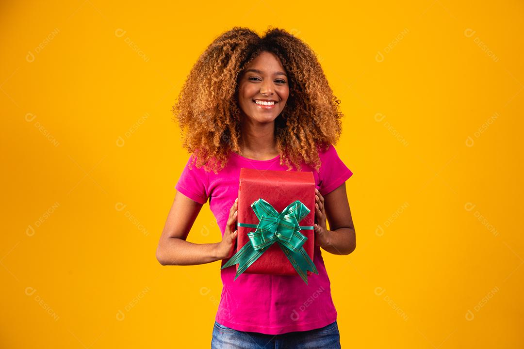 mulher afro segurando um presente na mão.