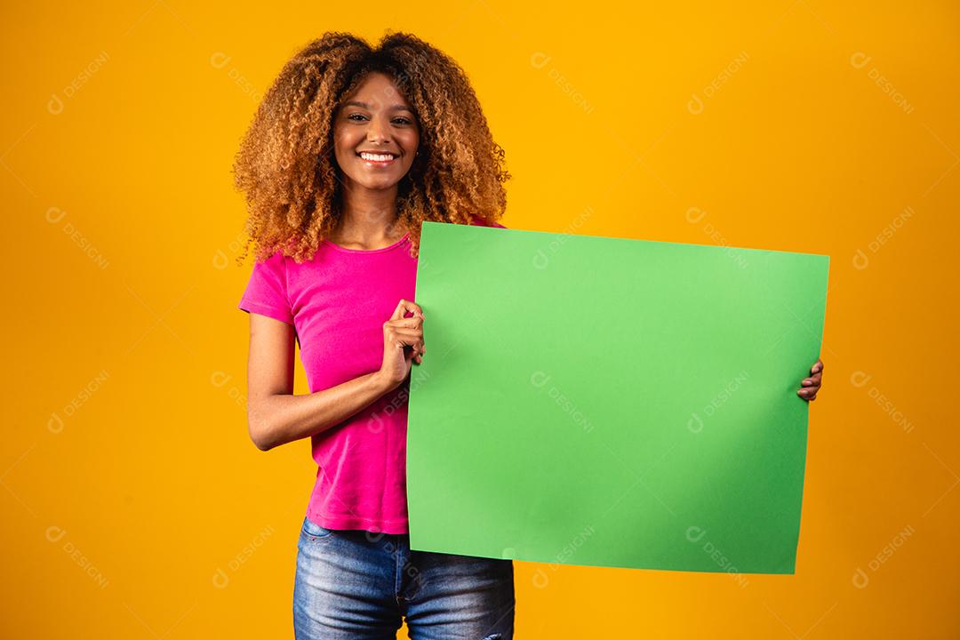 Mulher afro segurando um cartaz de croma verde.