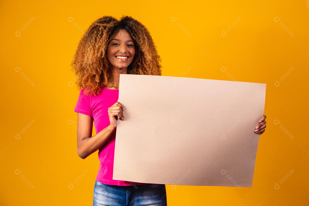 Mulher afro segurando cartolina marrom em fundo amarelo