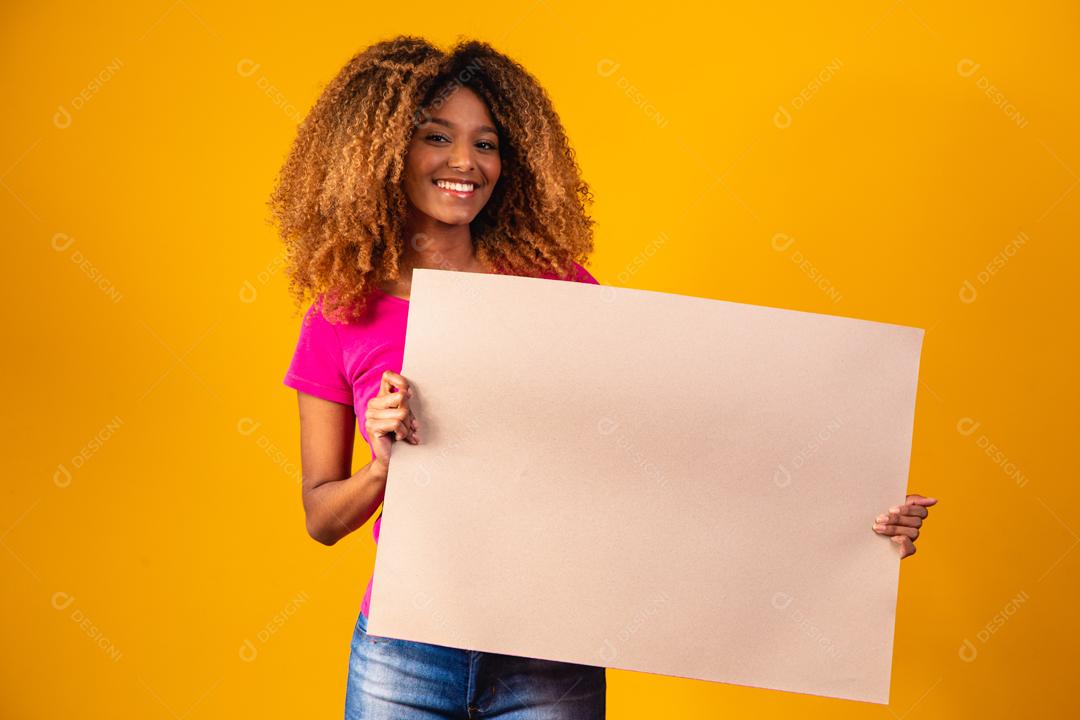 Mulher afro segurando cartolina marrom em fundo amarelo