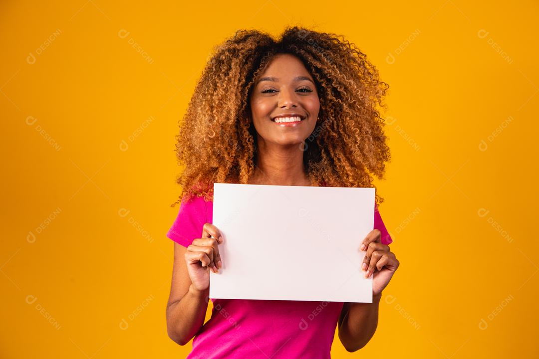 Mulher afro segurando cartolina marrom em fundo amarelo