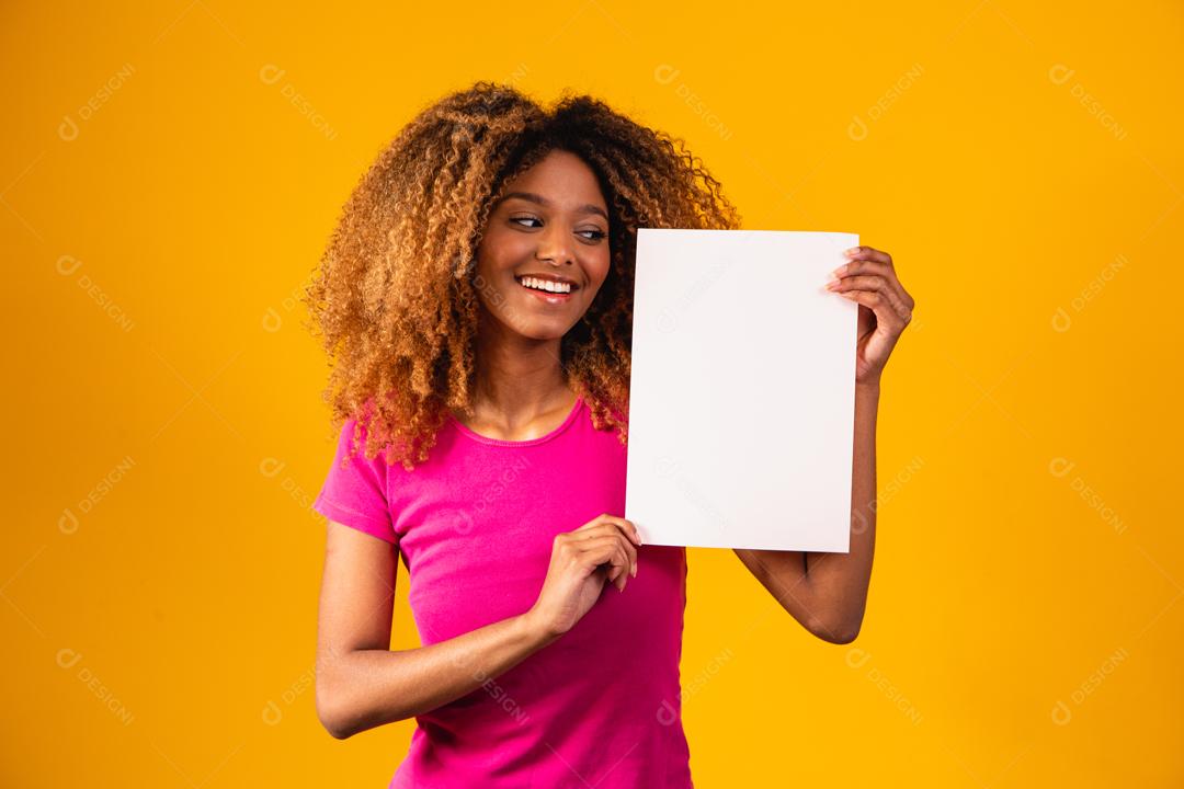 Mulher afro segurando Papel Branco em fundo amarelo