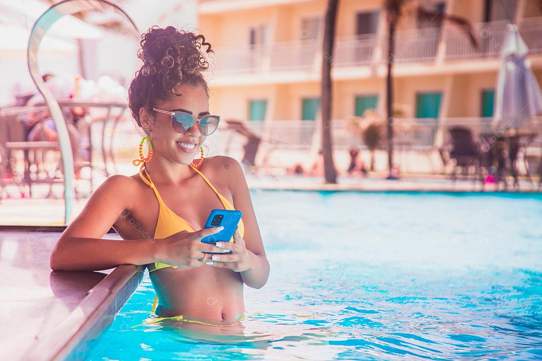 mulher trabalhando pelo celular na piscina do hotel