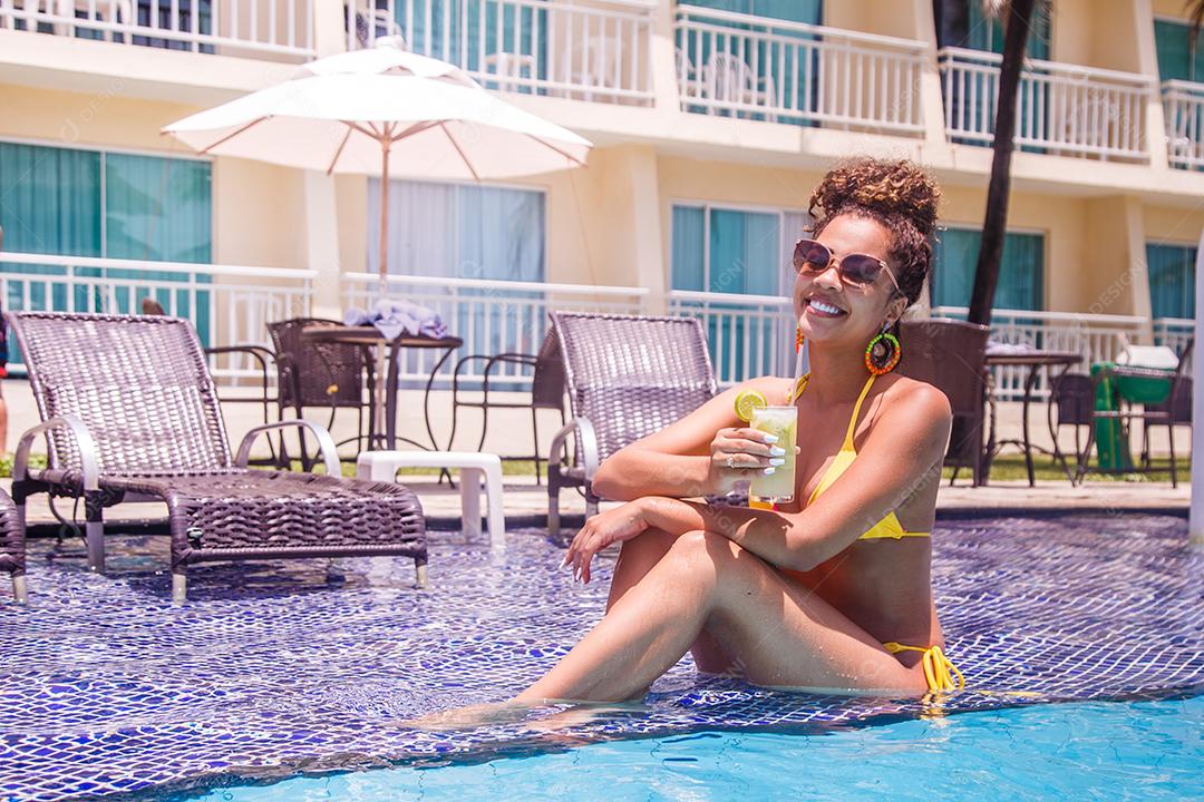 Jovem de férias na piscina do hotel tomando uma deliciosa bebida alcoólica.