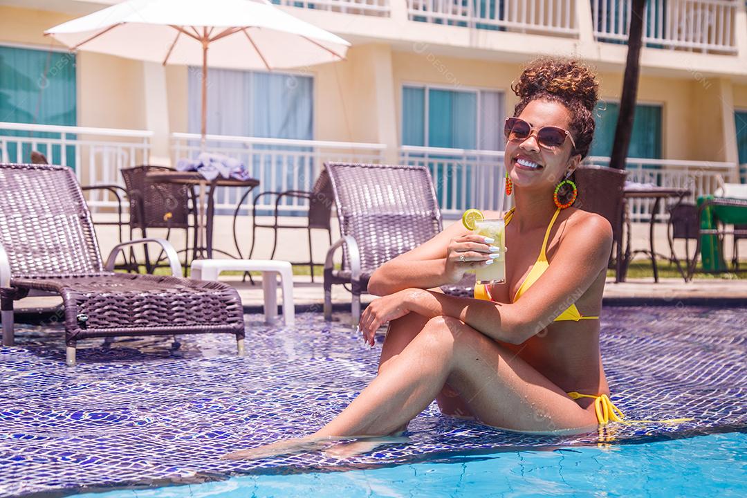 Jovem de férias na piscina do hotel tomando uma deliciosa bebida alcoólica.