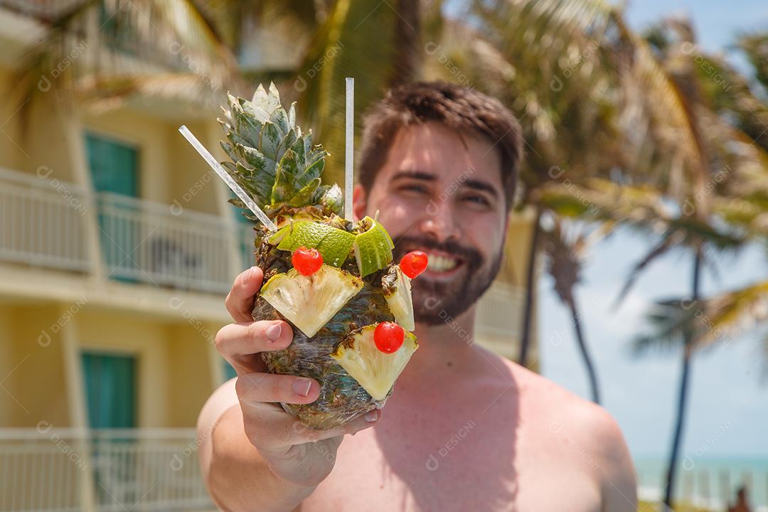 homem de férias em risort bebendo doce de abacaxi.