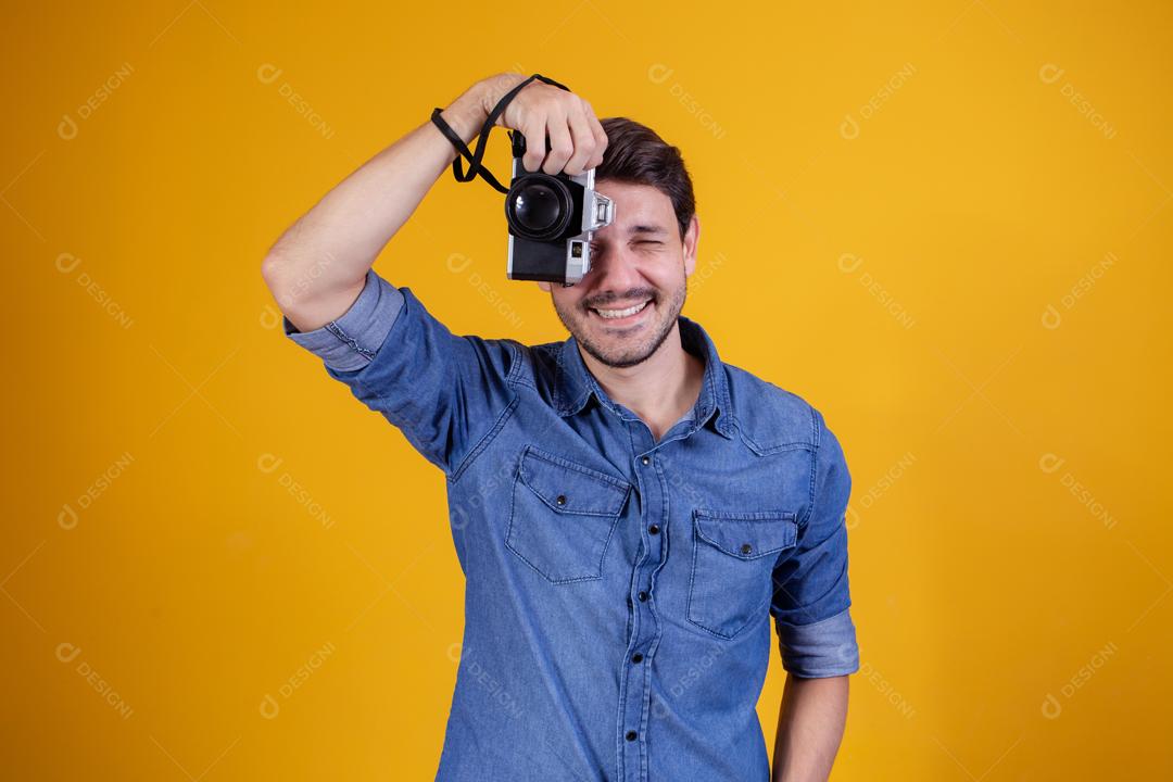 Fotógrafo em fundo amarelo homem com uma câmera fotográfica