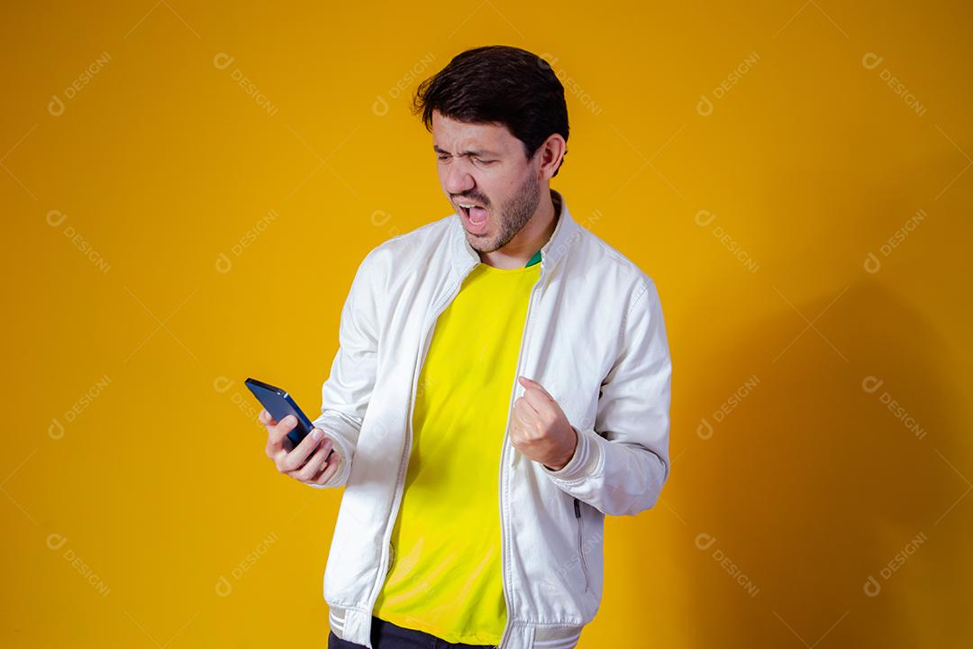 Torcedor da seleção brasileira de futebol comemorando um gol assistindo o smartphone