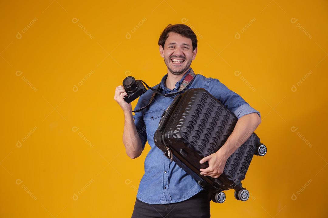 Homem com roupa social segurando mala preta e câmera