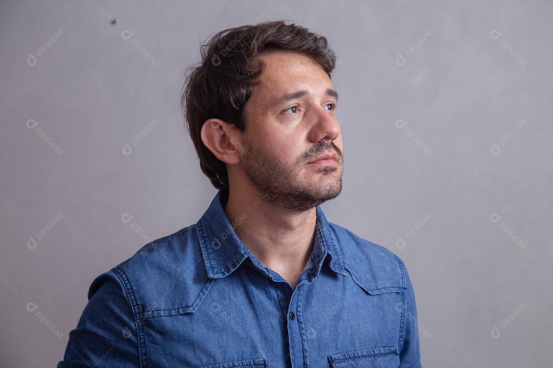 Homem  com roupa social camisa jeans e expressão de felicidade em fundo cinza