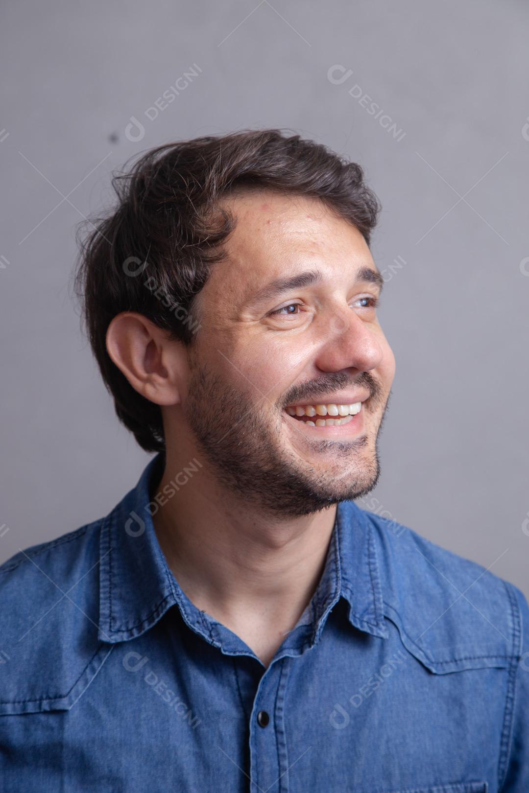 Homem  com roupa social camisa jeans e expressão de seria em fundo cinza