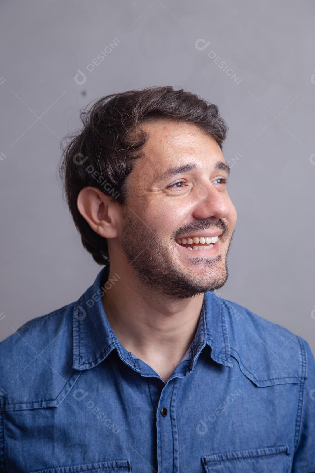 Homem  com roupa social camisa jeans e expressão de seria em fundo cinza