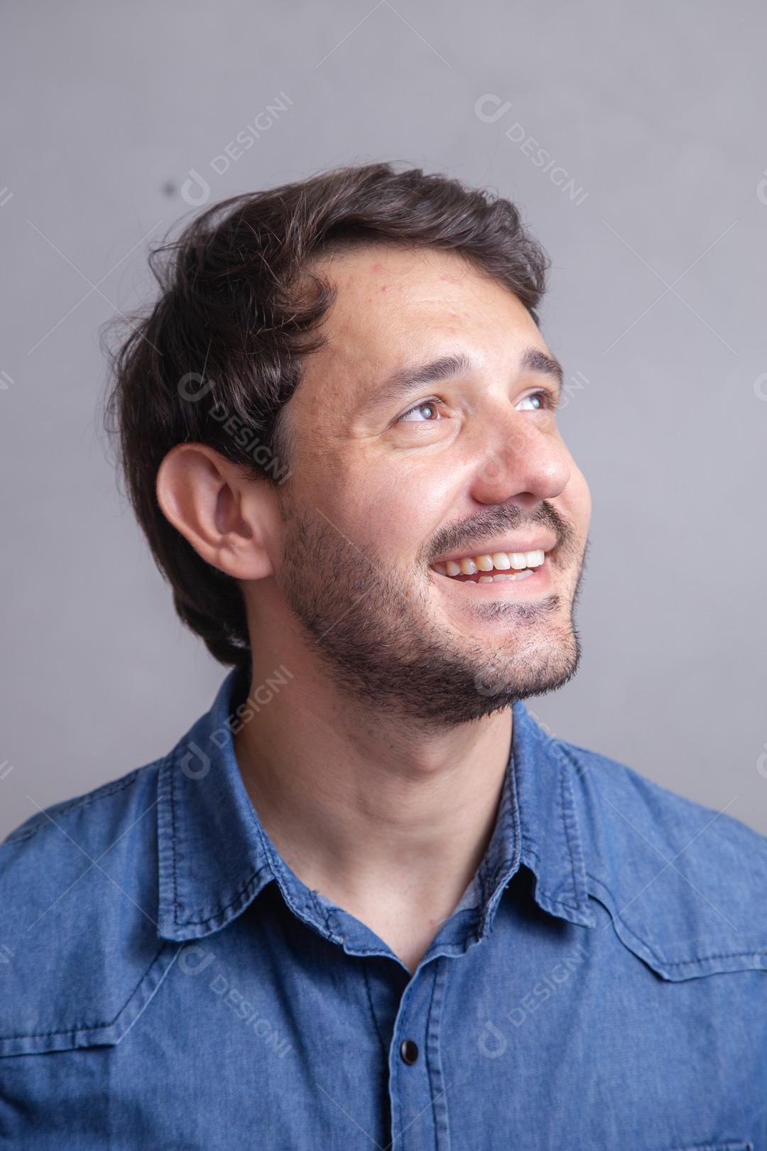 Homem  com roupa social camisa jeans e expressão de seria em fundo cinza