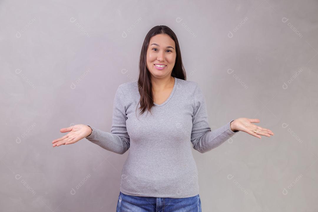 Mulher com os braços abertos e expressão de feliz em fundo cinza