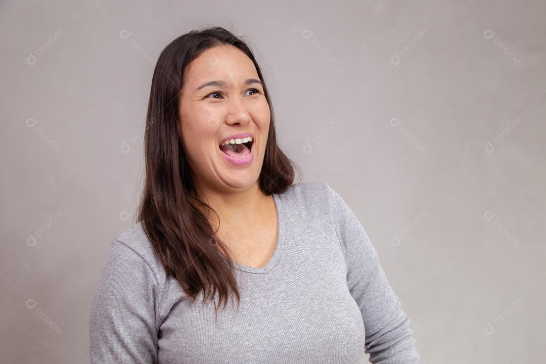 Mulher com expressão de feliz em fundo cinza