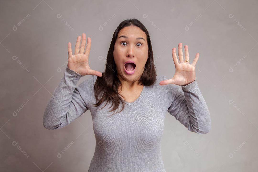 Mulher  com expressão de susto em fundo cinza