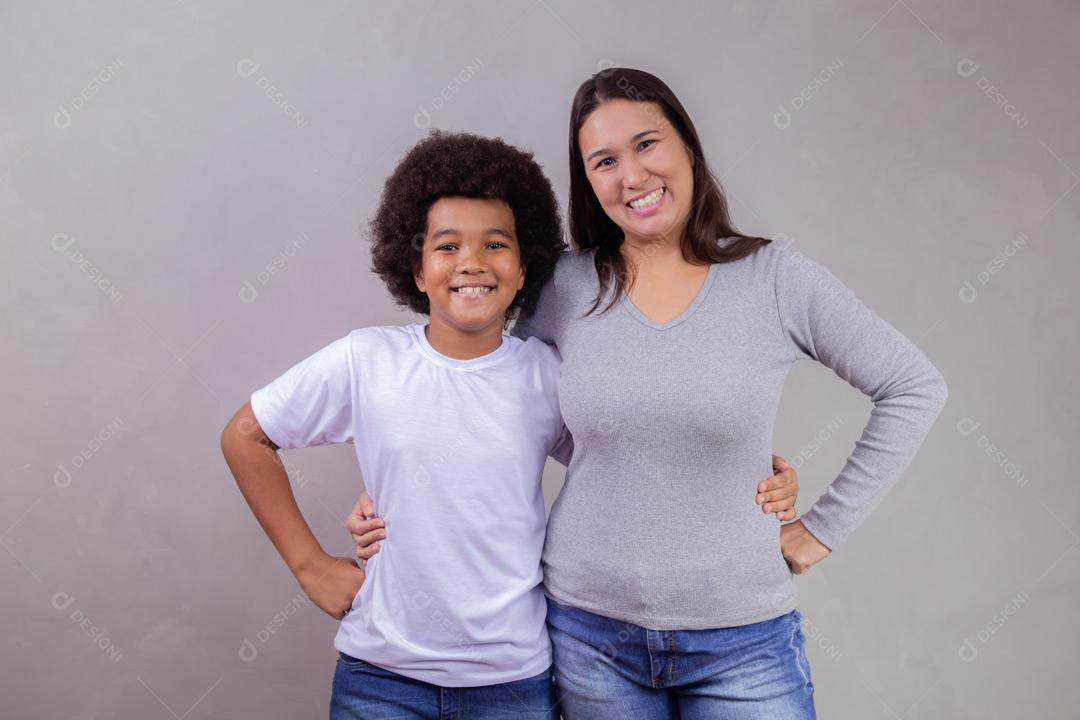 Mãe e filho abraçados com expressões de felicidade em fundo cinza