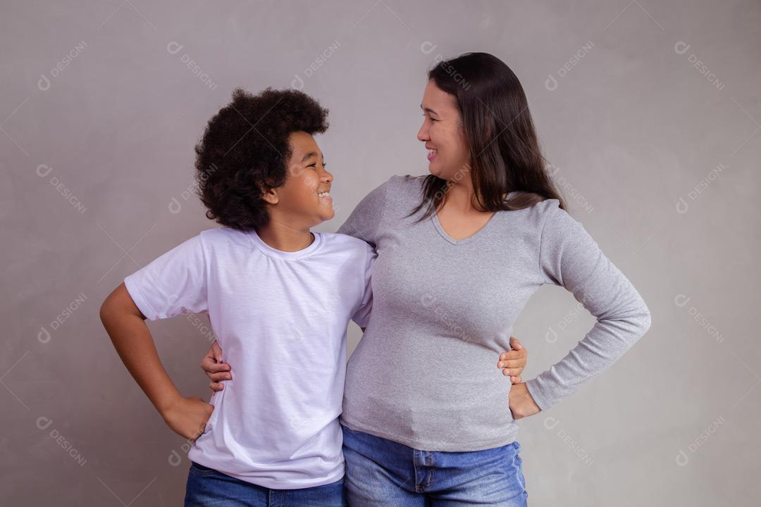 Mãe e filho abraçados com expressões de felicidade em fundo cinza