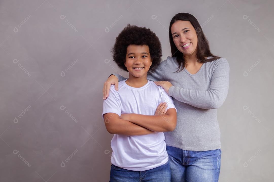 Mãe e filho abraçados com expressões de felicidade em fundo cinza