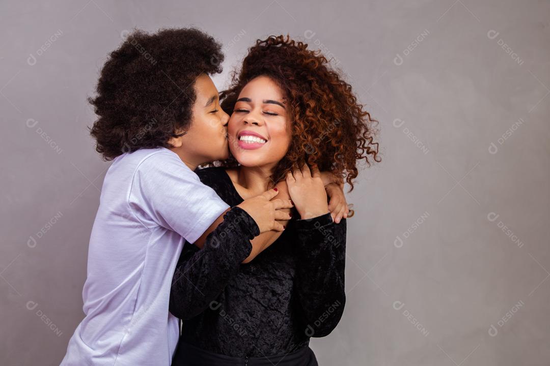 Mãe e filho abraçados com expressões de felicidade em fundo cinza