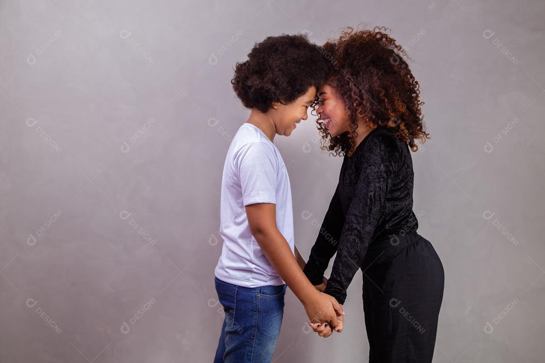 Mãe e filho abraçados com expressões de felicidade em fundo cinza