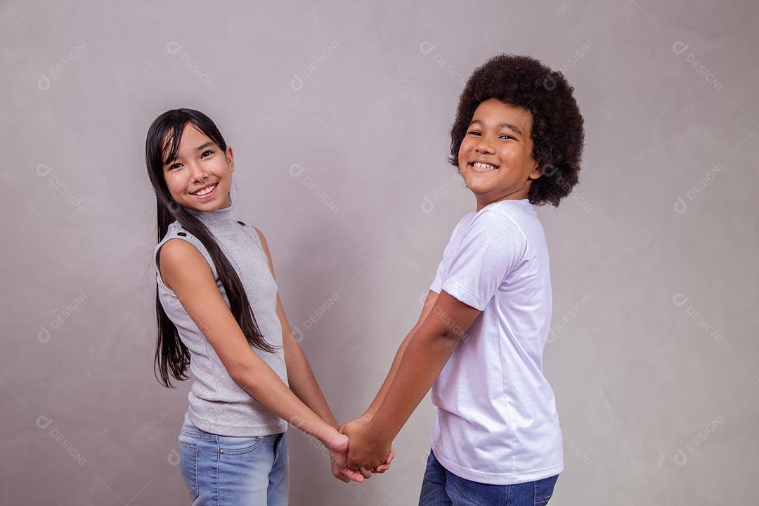 Casal de Crianças Japonesa e Afro de mãos dadas