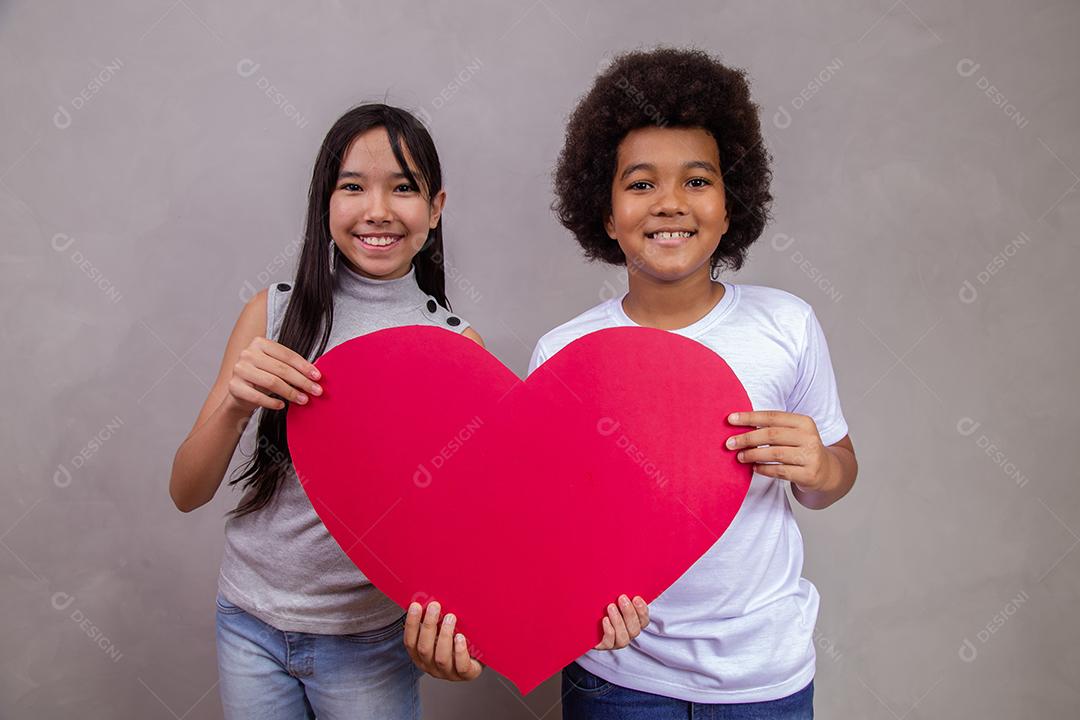 Criança japonesa e afro segurando um cartão em forma de coração