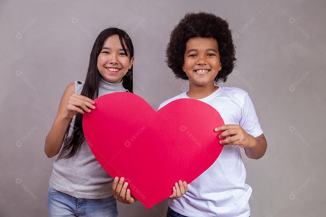 Criança japonesa e afro segurando um cartão em forma de coração