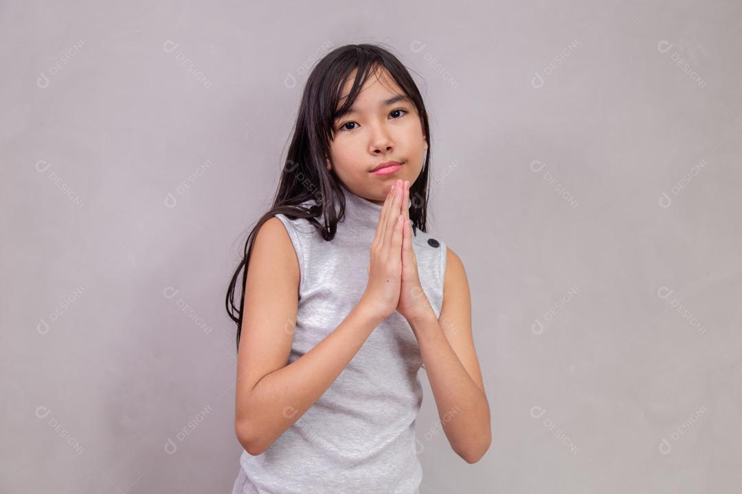 Criança japonesa de fazendo gesto de Pedido com expressão de Dó  em fundo cinza