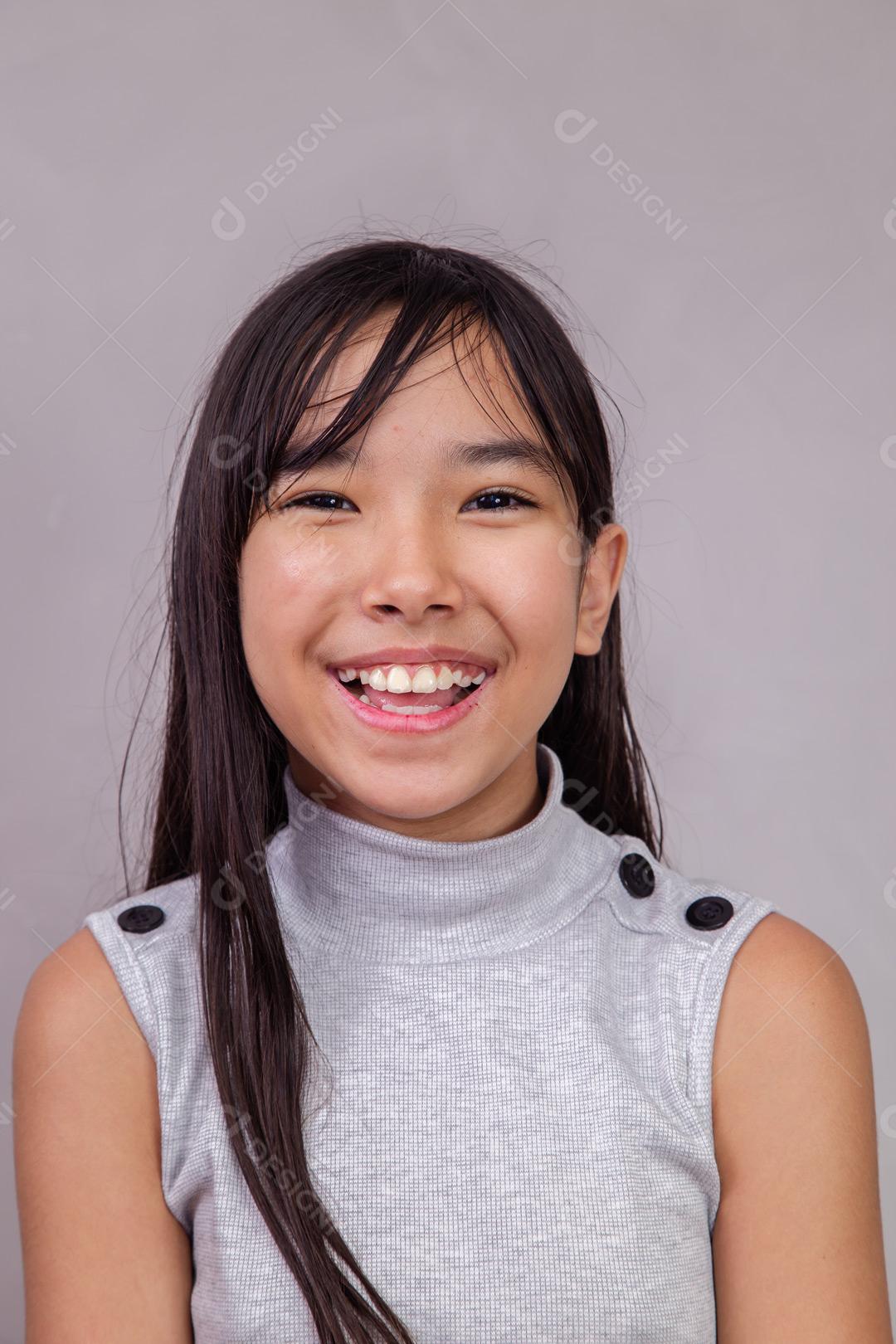 Criança japonesa  com expressão de feliz em fundo cinza