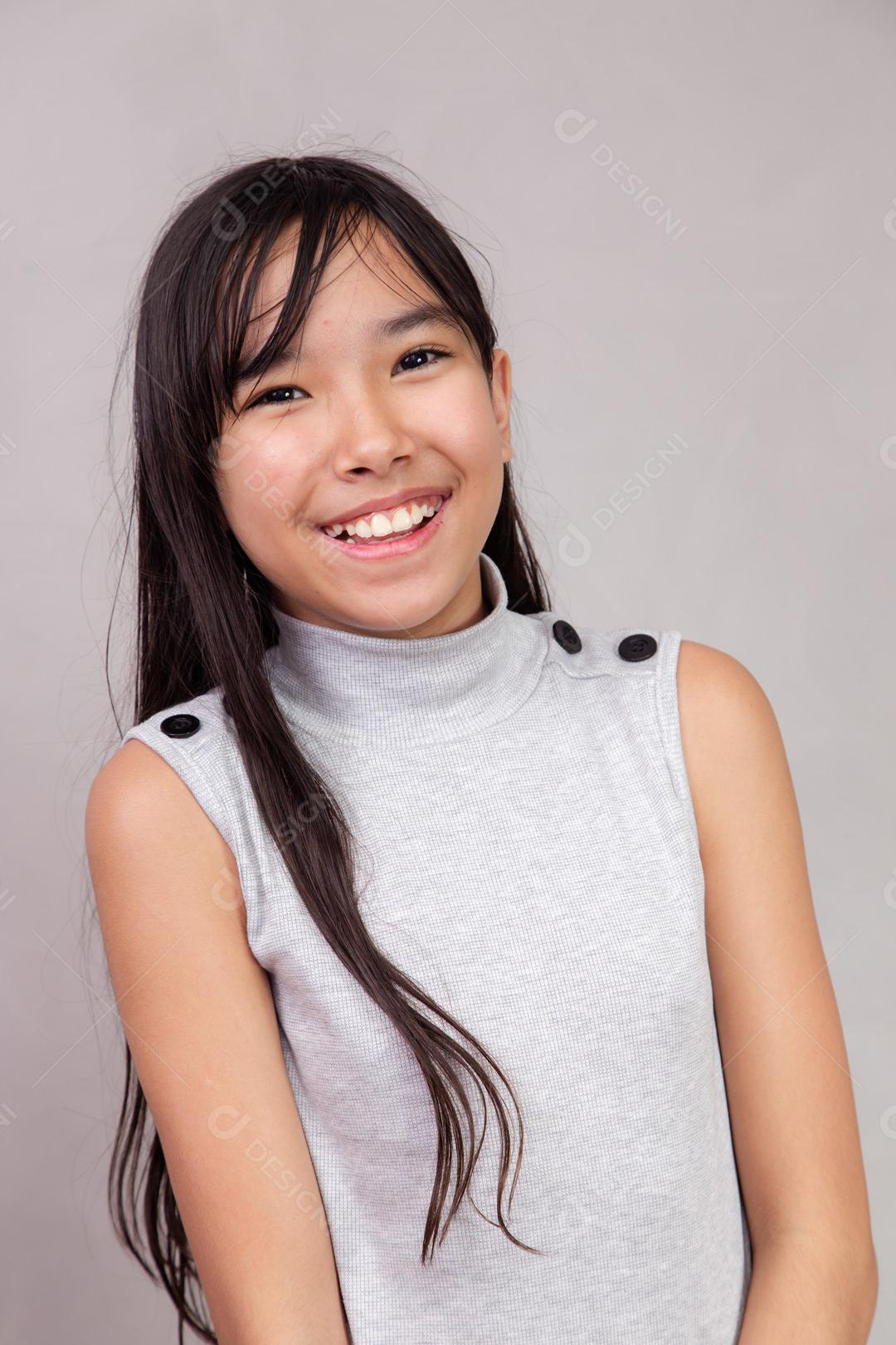Criança japonesa  com expressão de feliz em fundo cinza