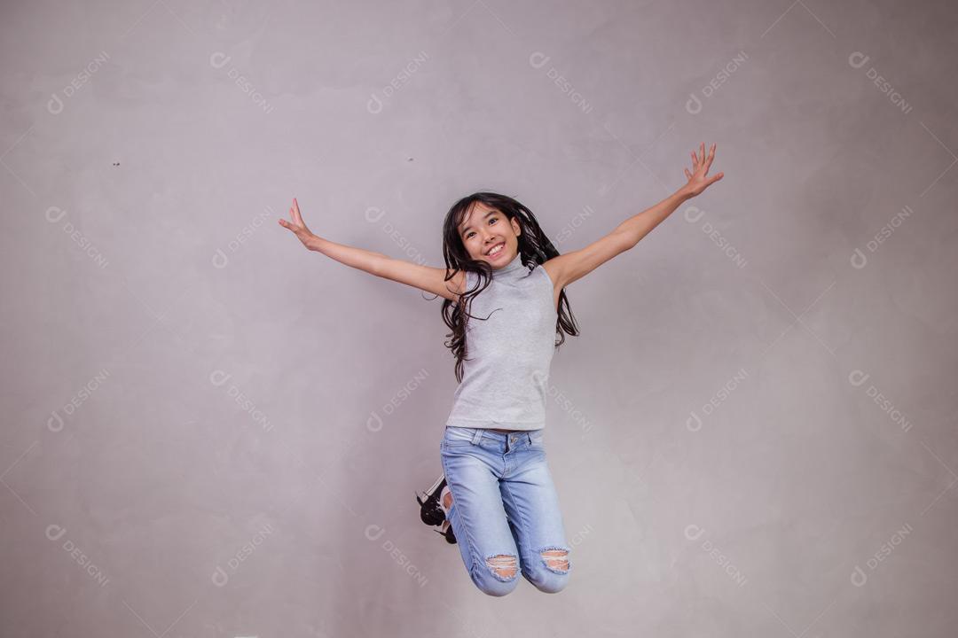 Criança japonesa  com expressão de feliz Pulando em fundo cinza