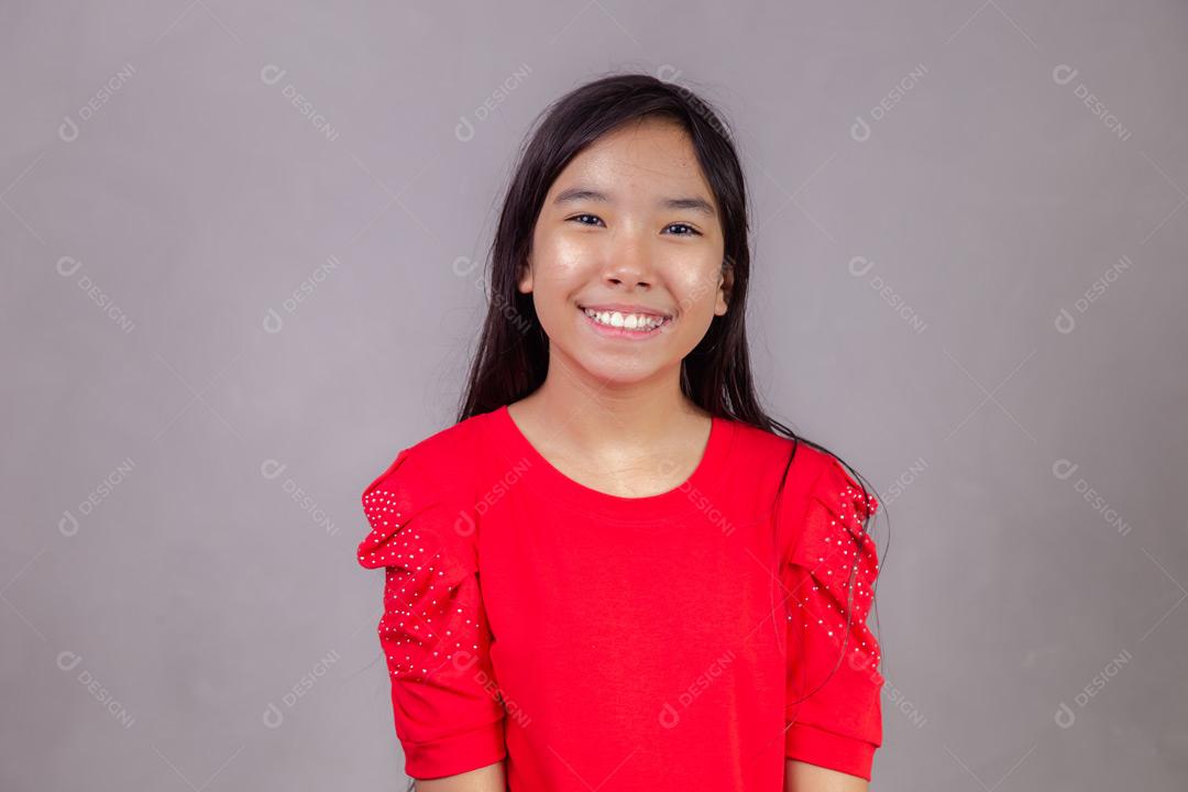 Criança japonesa com expressão de feliz em fundo cinza