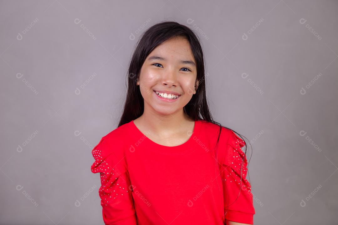 Criança japonesa com expressão de feliz em fundo cinza