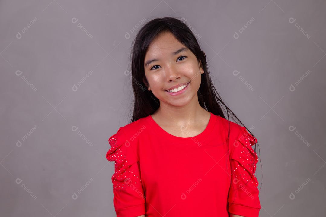 Criança japonesa com expressão de feliz em fundo cinza
