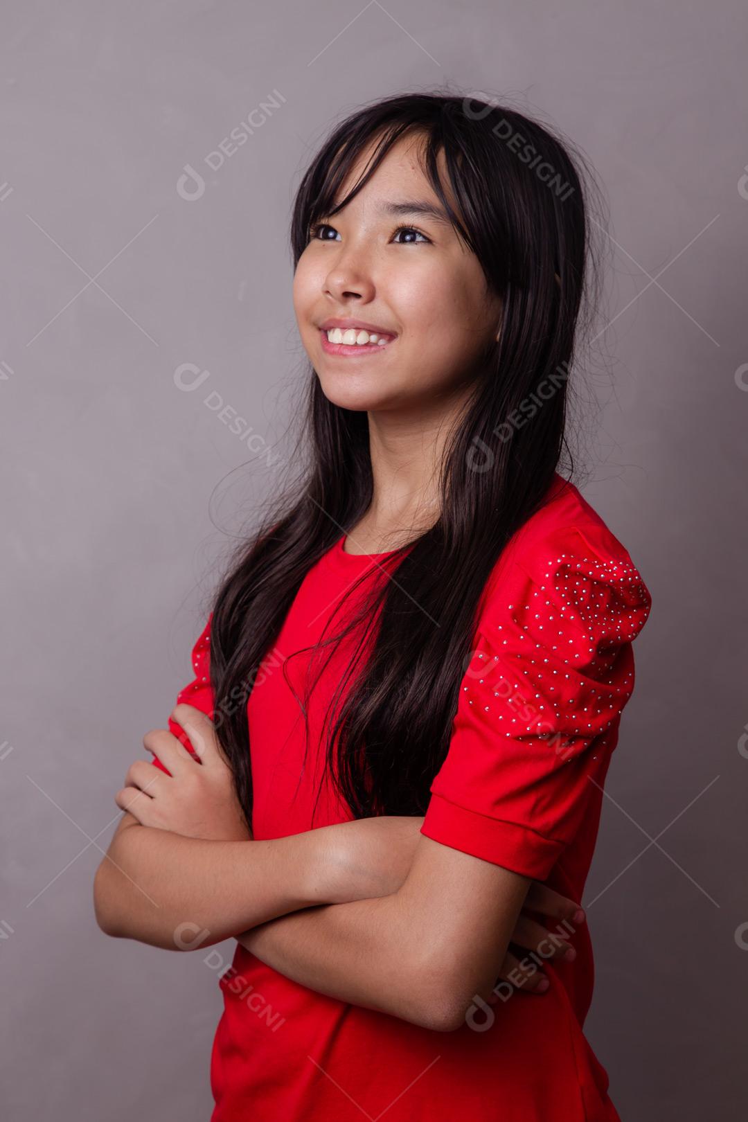 Criança japonesa com expressão de feliz braços cruzados  em fundo cinza