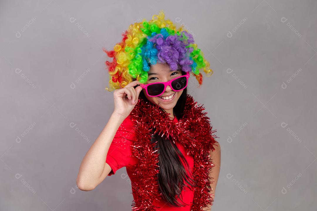 Criança japonesa com peruca colorida e óculos escuro e roupa vermelha em fundo cinza