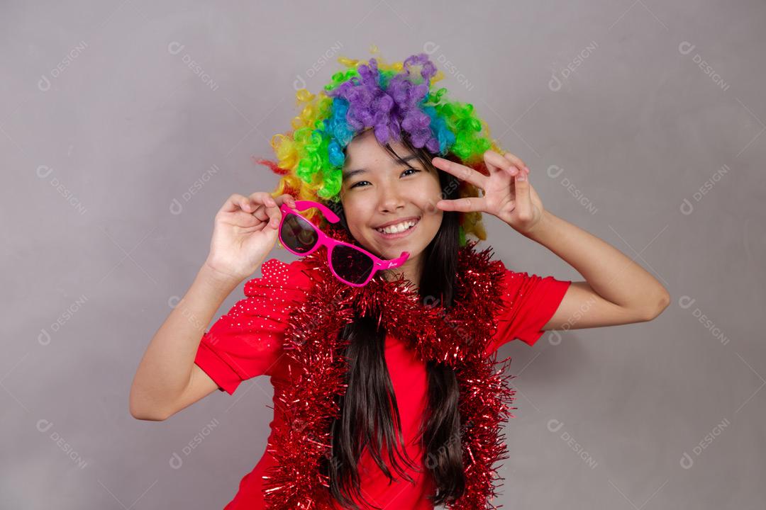 Criança japonesa com peruca colorida e óculos escuro e roupa vermelha em fundo cinza