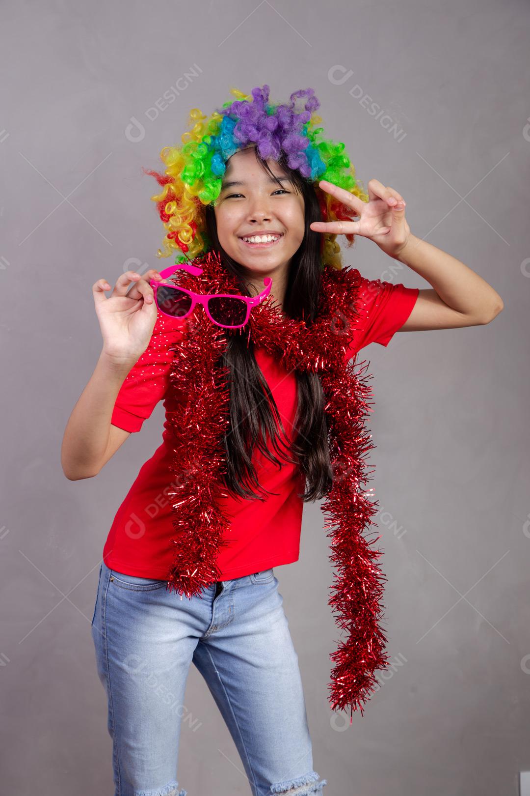 Criança japonesa com peruca colorida e óculos escuro e roupa vermelha em fundo cinza